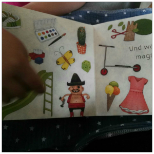 Eine aufgeschlagene Buchseite auf der mehrere Dinge zu sehen sind, zB Eis, ein Kleid, ein Schmetterlink, ein Roller,...